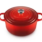 Le Creuset vs Staub Dutch ovens side by side on a kitchen counter, showing their different enamel finishes and lid designs.